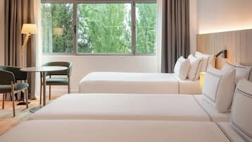 A hotel room with two beds, a desk, and a chair.