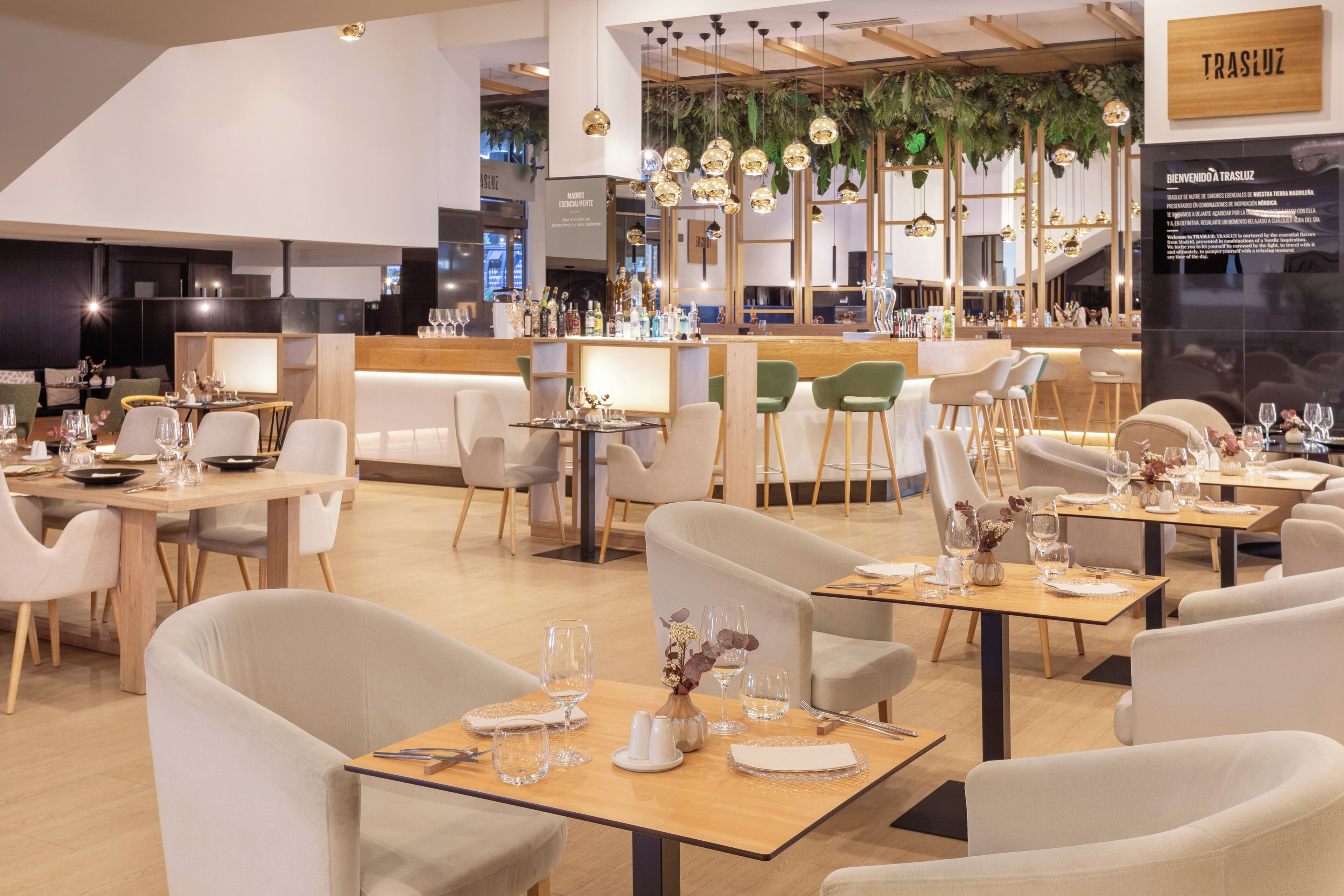 Un interior de restaurante moderno con varias mesas, sillas y una zona de bar.