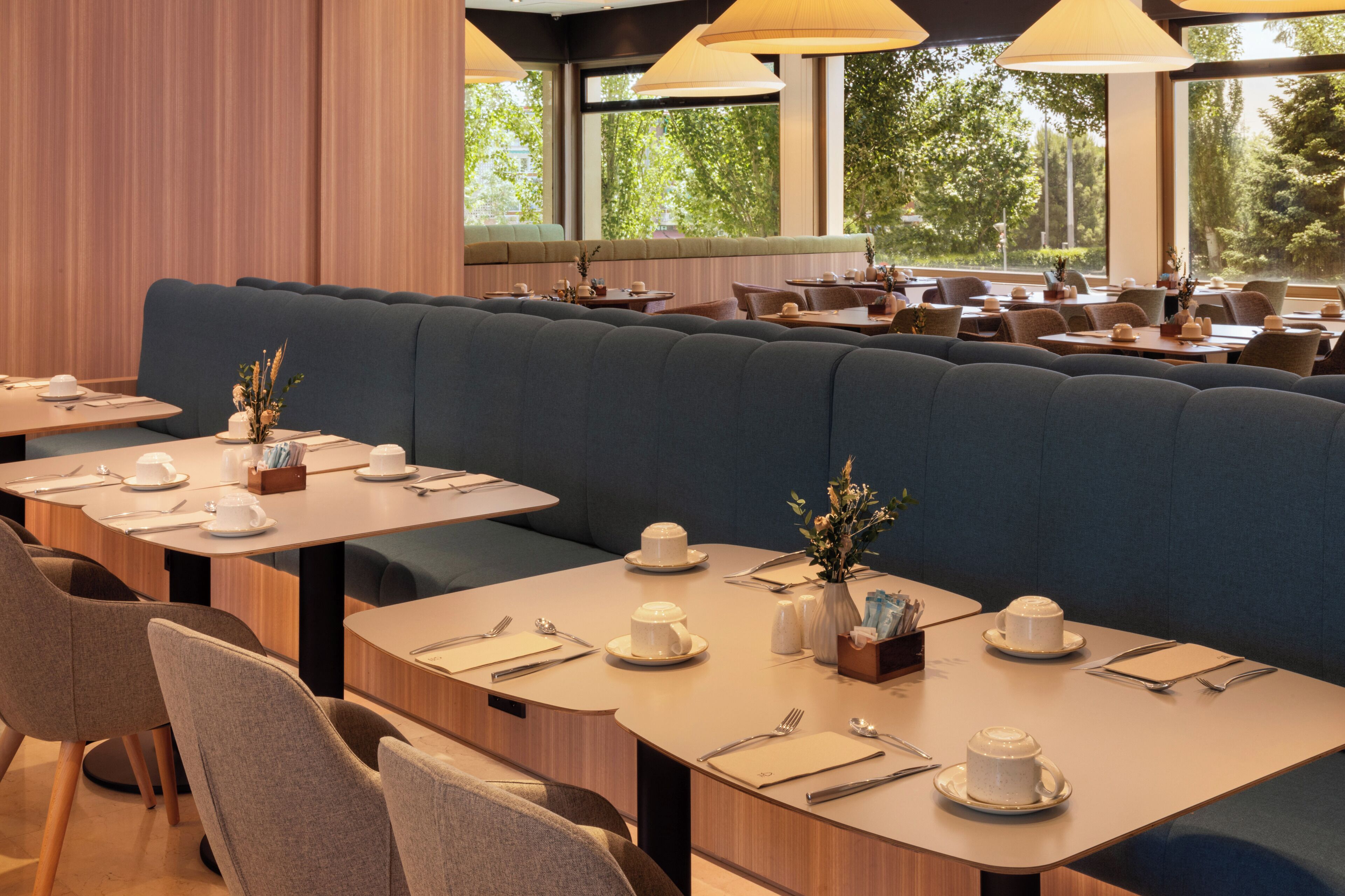 A restaurant with booths, tables, and a view of trees.