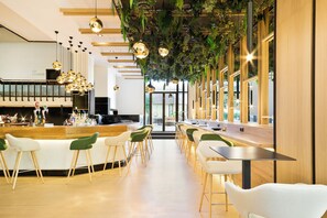 A modern bar area with a long counter, multiple bar stools, and hanging pendant lights.