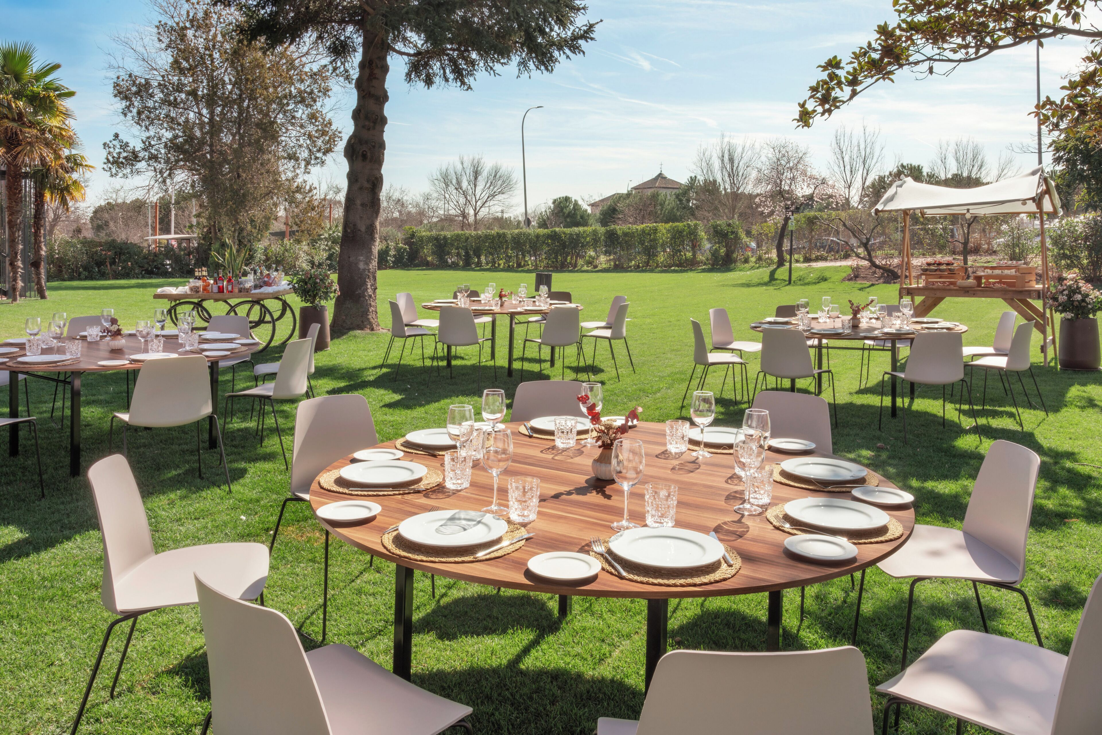 Un área de comedor al aire libre con mesas redondas, sillas y un césped.