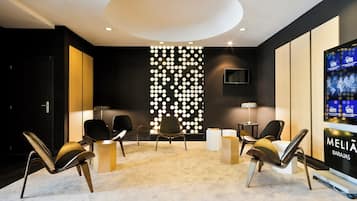 A modern lobby with a reception desk, seating area, and a large screen displaying the hotel name.