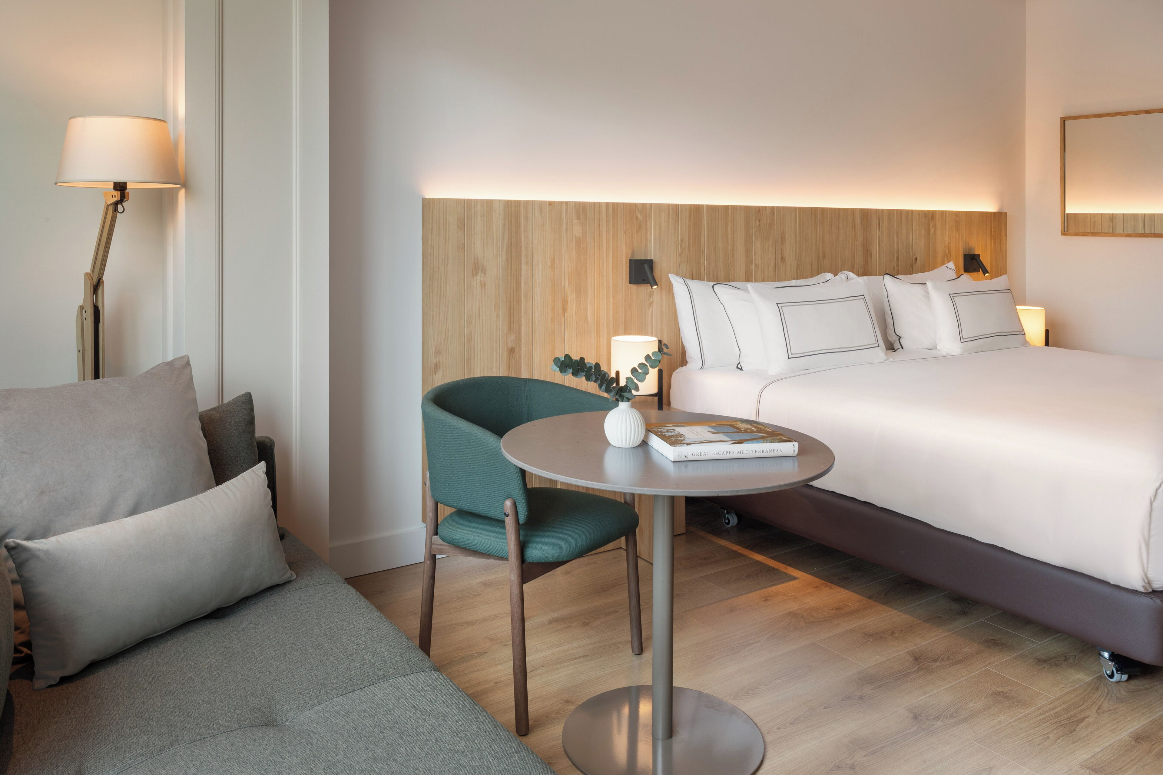 Una habitación de hotel con una cama, un sofá, una mesita y una silla.