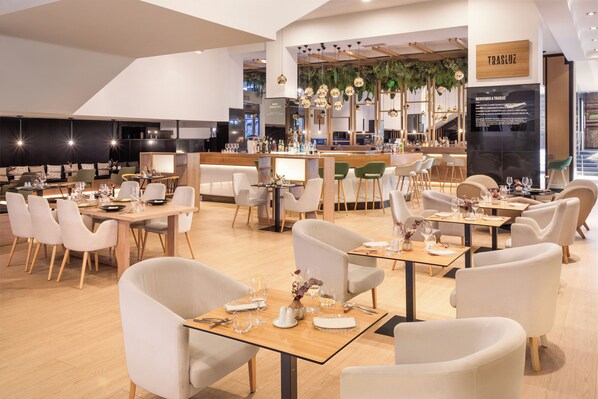 Un restaurant moderne doté de plusieurs tables et chaises, d’un bar et d’une enseigne indiquant « TRASLIZ ».