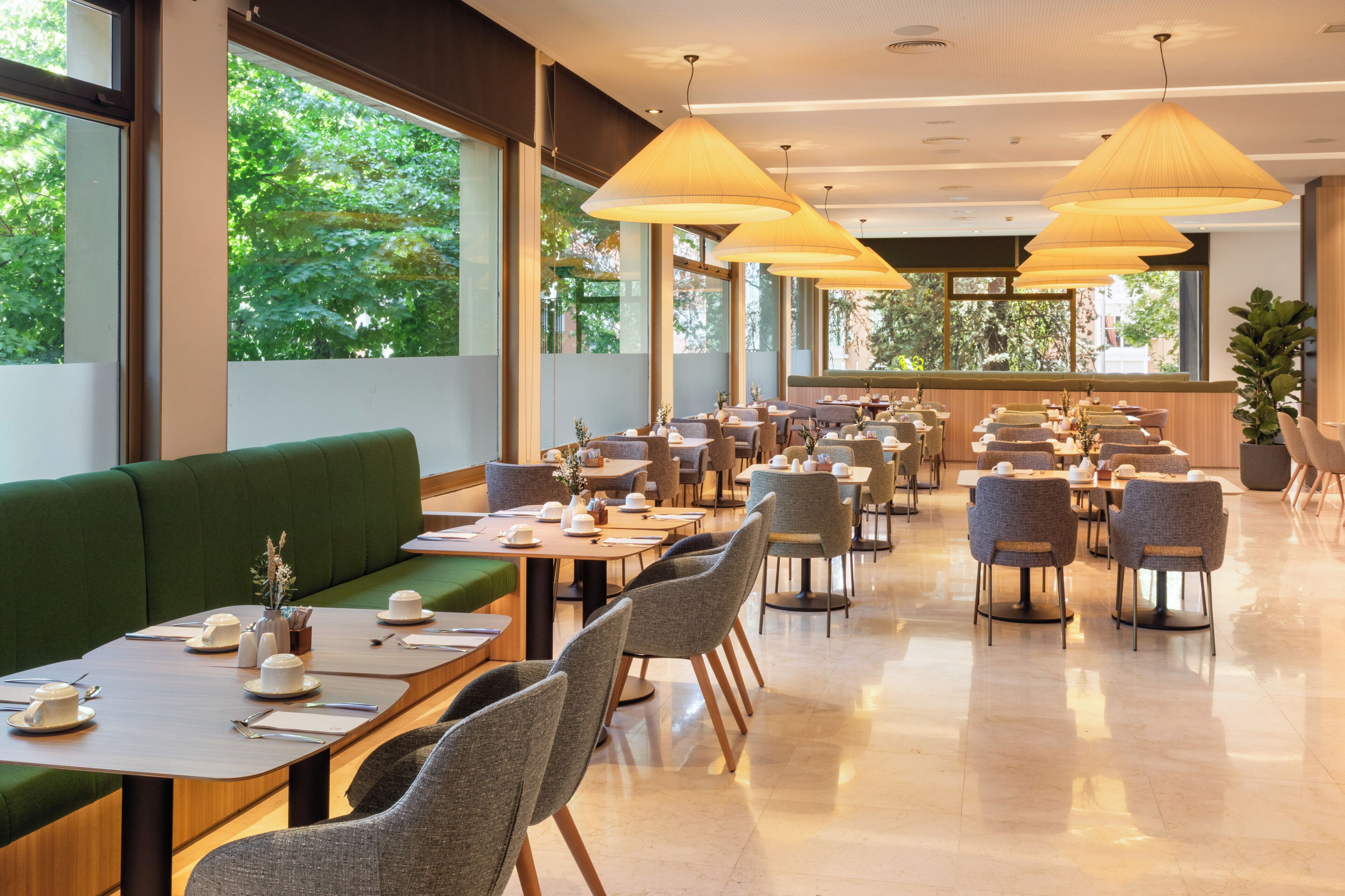 A spacious restaurant with high ceilings, large windows, and a variety of seating arrangements including booths and tables.