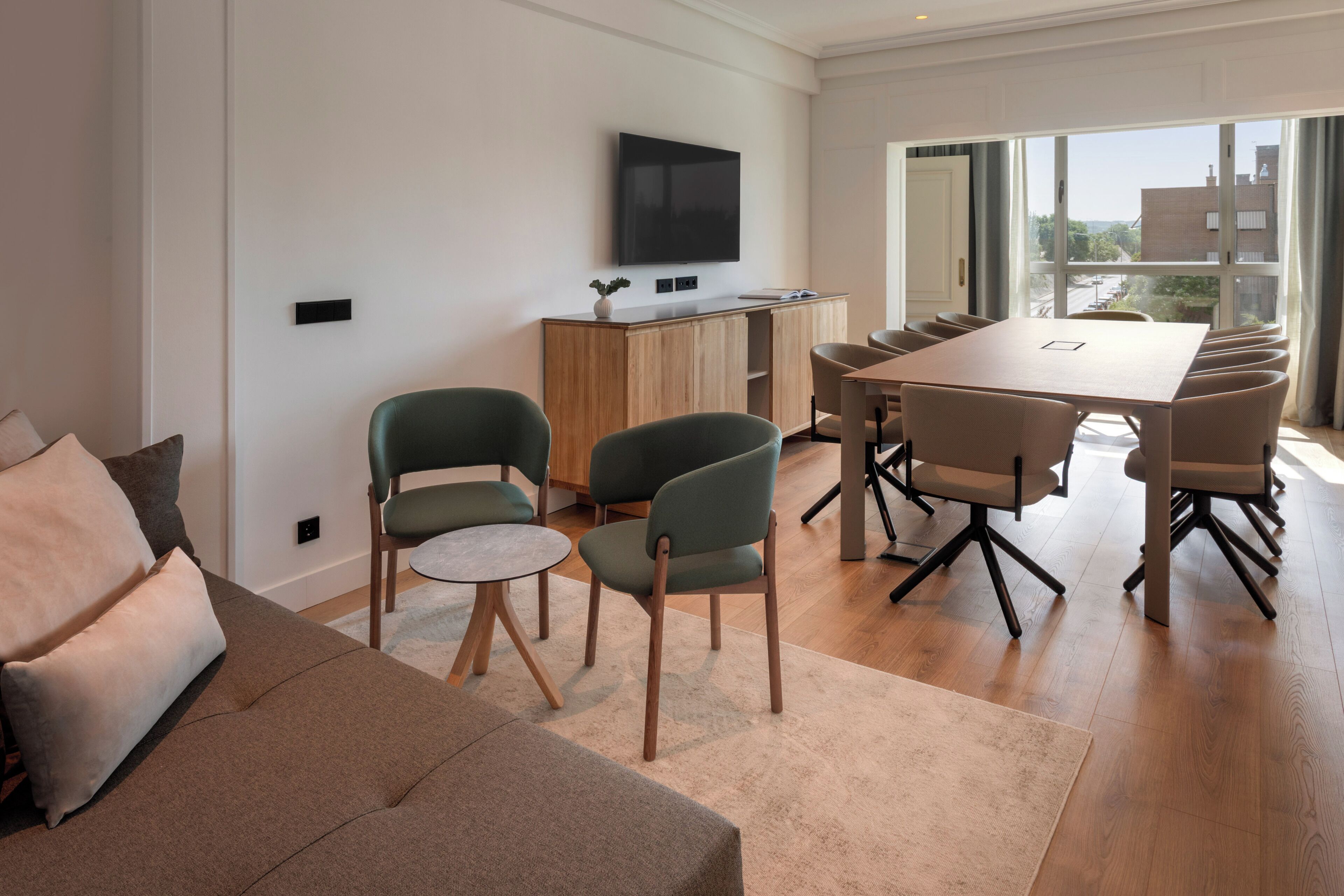 Una sala de estar moderna con un sofá, sillas, una mesa de comedor y un televisor montado en la pared.