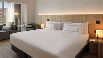 Una habitación de hotel con una cama grande, una mesita, una silla y un sofá.