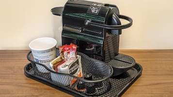 Een koffiezetapparaat met een lekbak, een koffiekopje en een mok op een dienblad.
