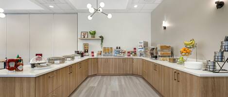 A modern kitchen with a curved counter, wooden cabinets, and various food items and kitchen appliances.
