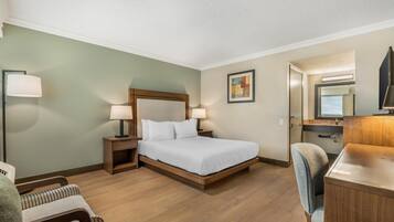 A hotel room with a bed, bedside tables, a desk, a chair, and a mirror.