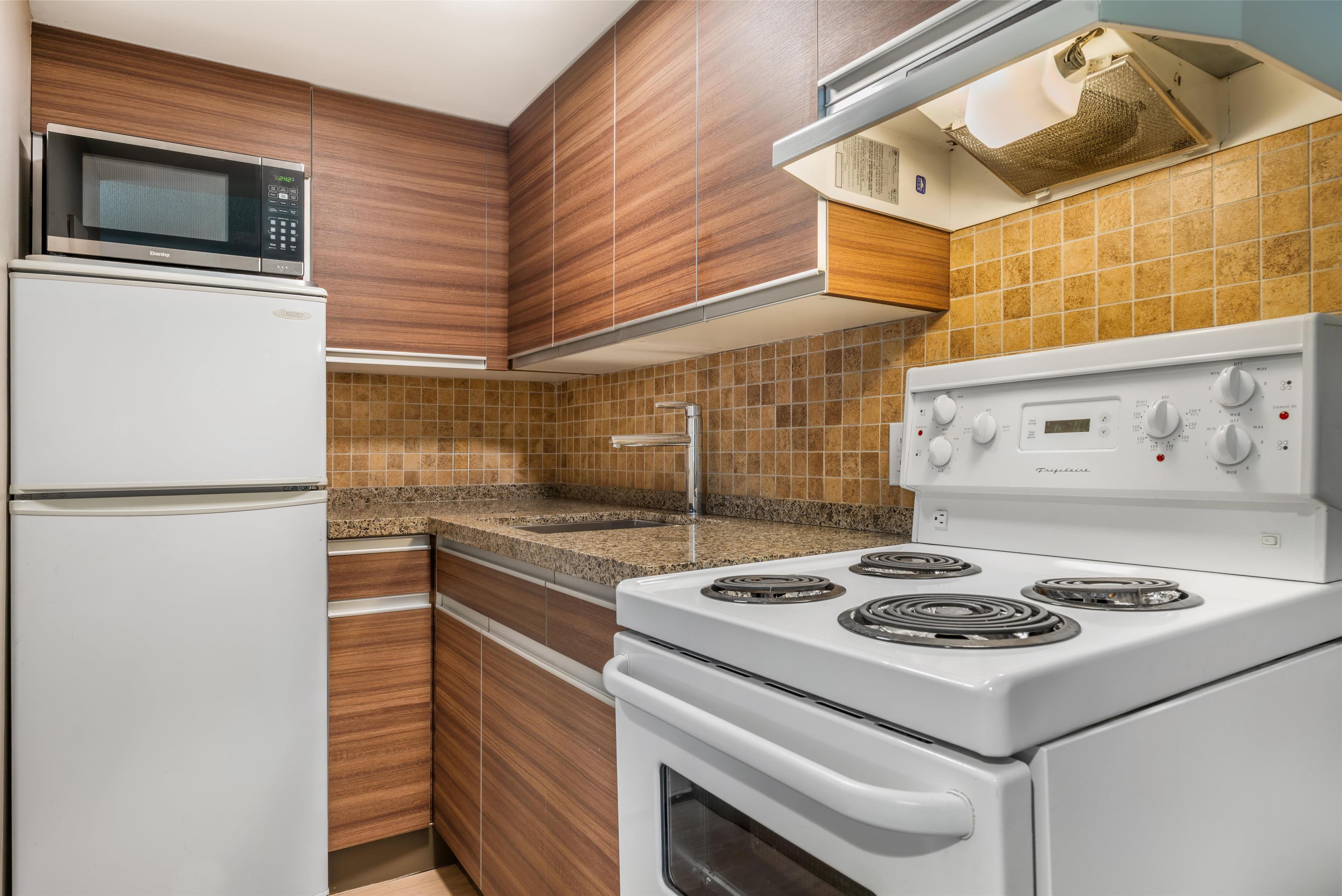 A kitchen with a white refrigerator, microwave, stove, and oven.