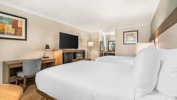 Habitación de hotel con una cama grande, un escritorio con silla, un televisor de pantalla plana, un microondas y una lámpara.