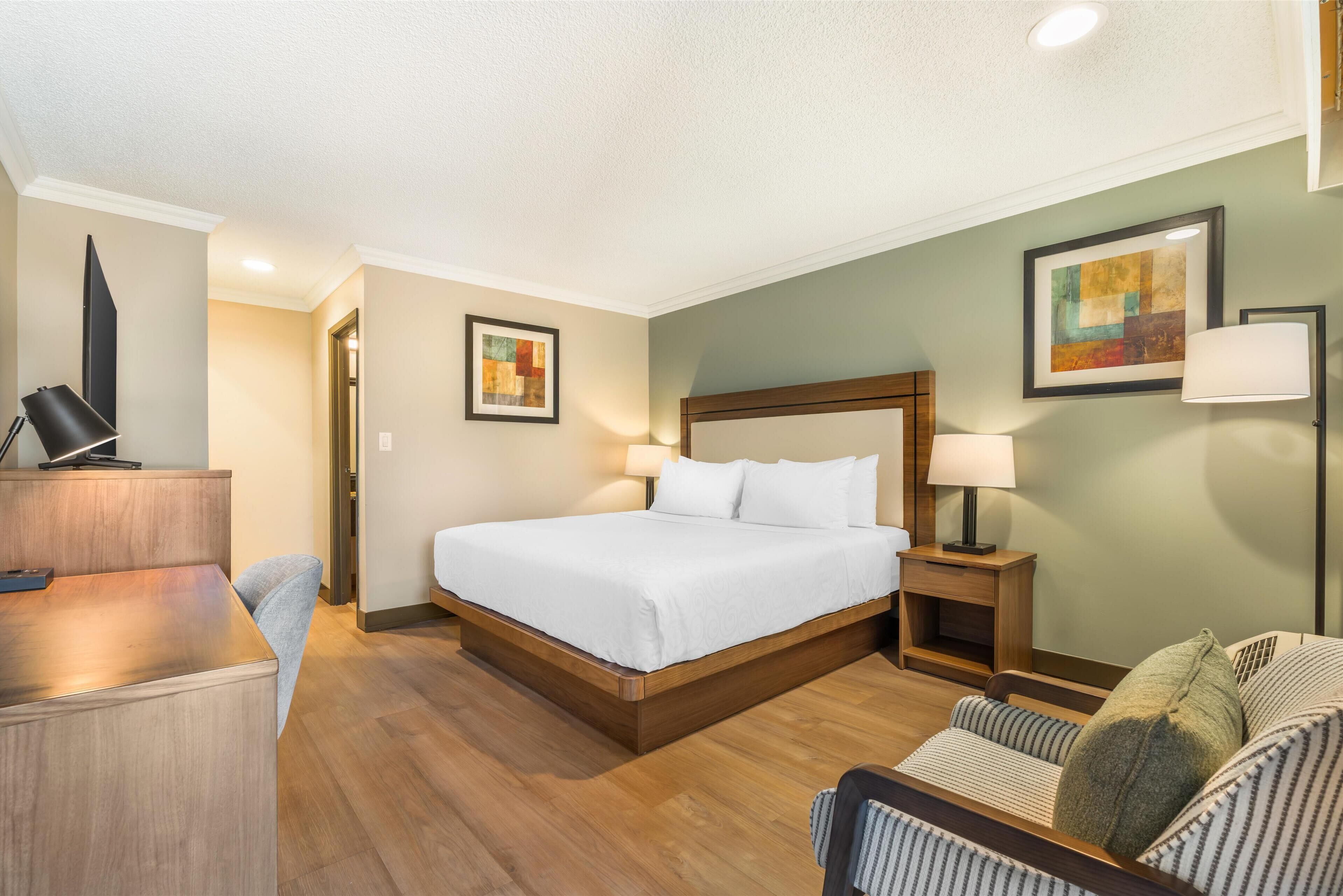 Une chambre d’hôtel avec un grand lit, des tables de chevet, un bureau et une chaise.