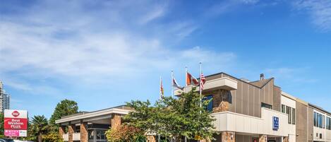 A Best Western Plus hotel with a modern design, a parking lot, and flags.