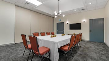 A conference room with a white table, orange chairs, a ceiling light, and a door.