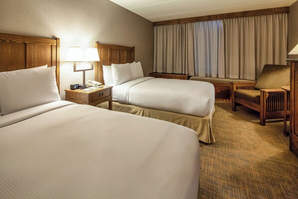 A hotel room with two beds, a nightstand with a lamp, a chair, and a window with curtains. - DoubleTree by Hilton Libertyville - Mundelein (Mundelein)