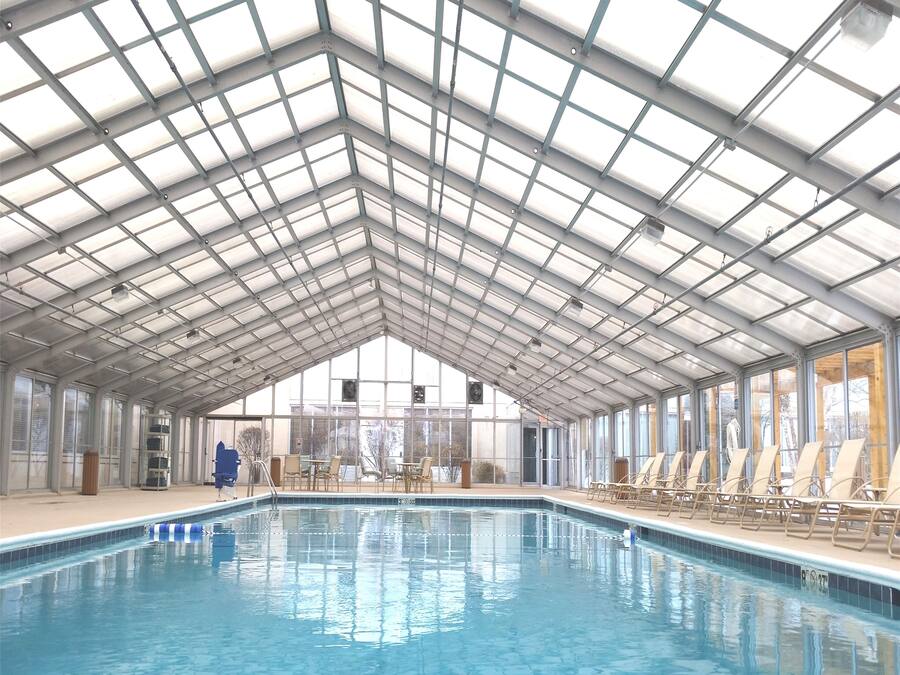 Una piscina interior con techo de vidrio alto y vistas al exterior.