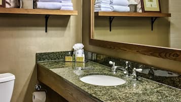Un baño con inodoro, lavamanos y espacio para toallas.