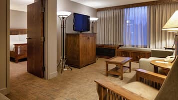 Ett hotellrum med ett träskåp, en tv, en soffa, ett litet bord och en lampa.