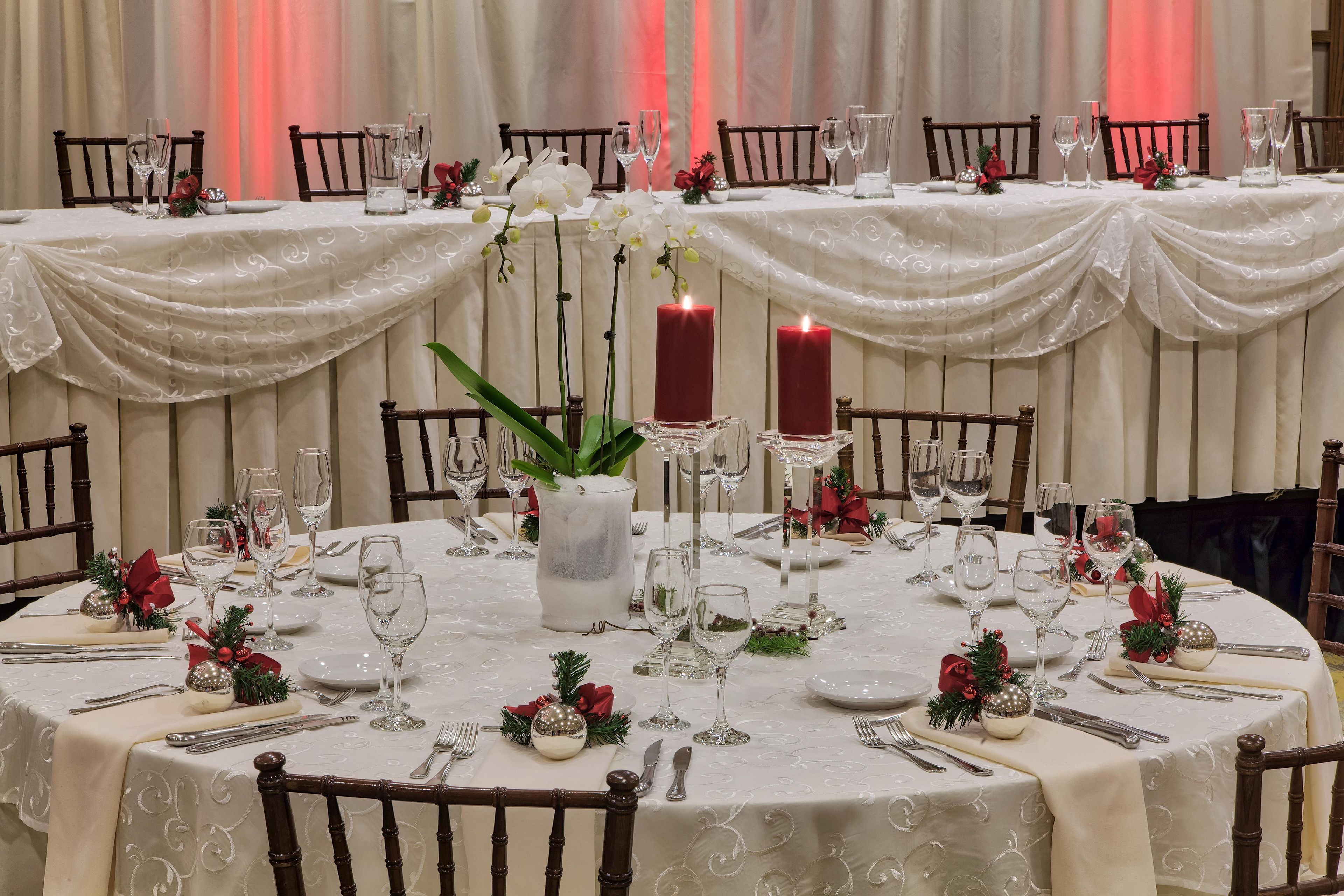Mesa redonda para comedor dispuesta para un evento formal, con mantel blanco, velas y cristalería.