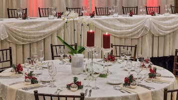 Mesa redonda para comedor dispuesta para un evento formal, con mantel blanco, velas y cristalería.