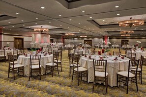 Un salón de banquetes con mesas redondas, sillas y candelabros.