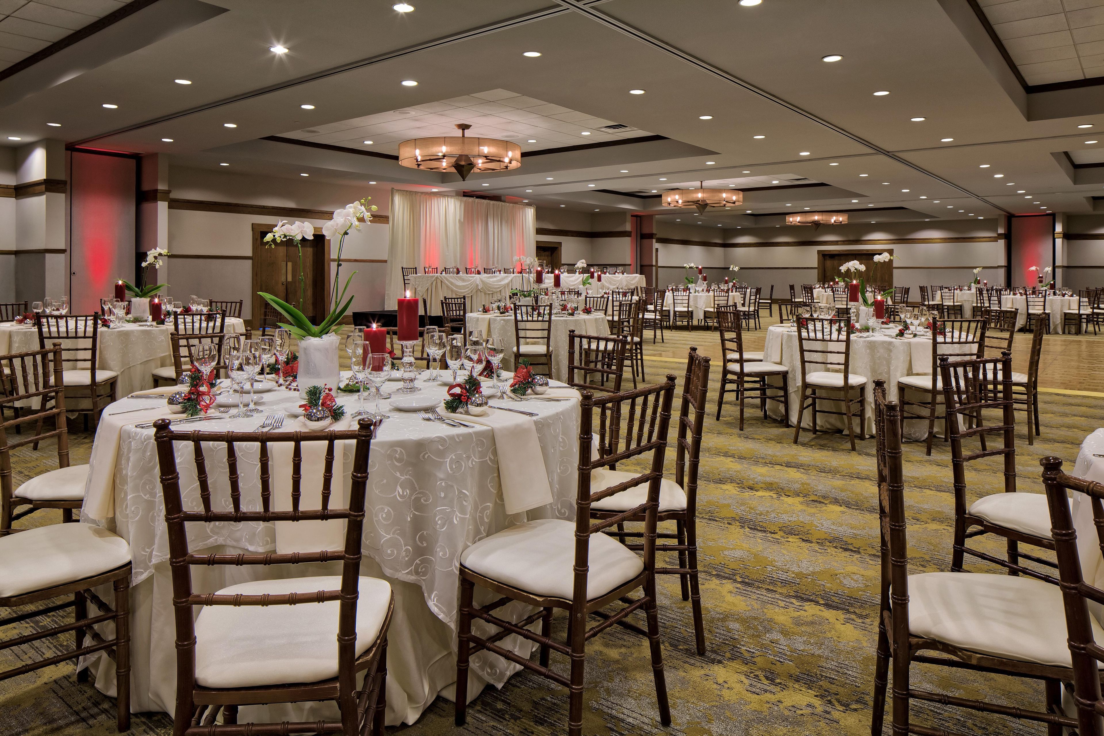 A banquet hall with round tables, chairs, and a chandelier.