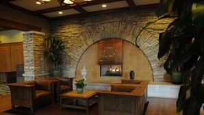 A cozy living area with a stone fireplace, wooden furniture, and a large potted plant.