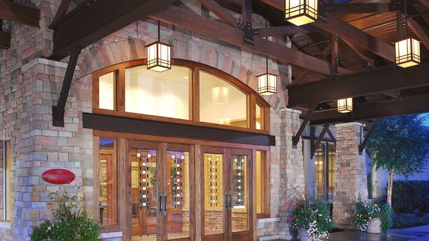 A stone building with a wooden facade, large glass doors, and a covered entrance area with hanging lanterns.
