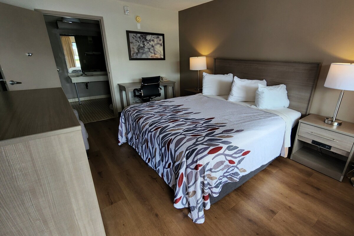 Ein Hotelzimmer mit Bett, Nachttischlampen, Schreibtisch und Stuhl.
