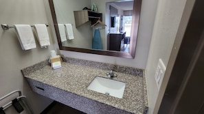 A bathroom with a granite countertop, a white sink, a mirror, and a towel rack with three towels. - Red Roof Inn Perry (Perry)