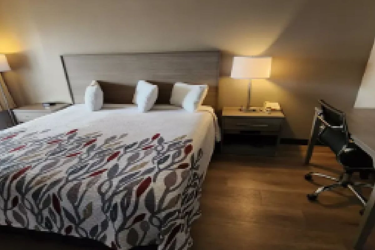 Una habitación de hotel con cama, dos mesitas de noche, un escritorio y una silla.