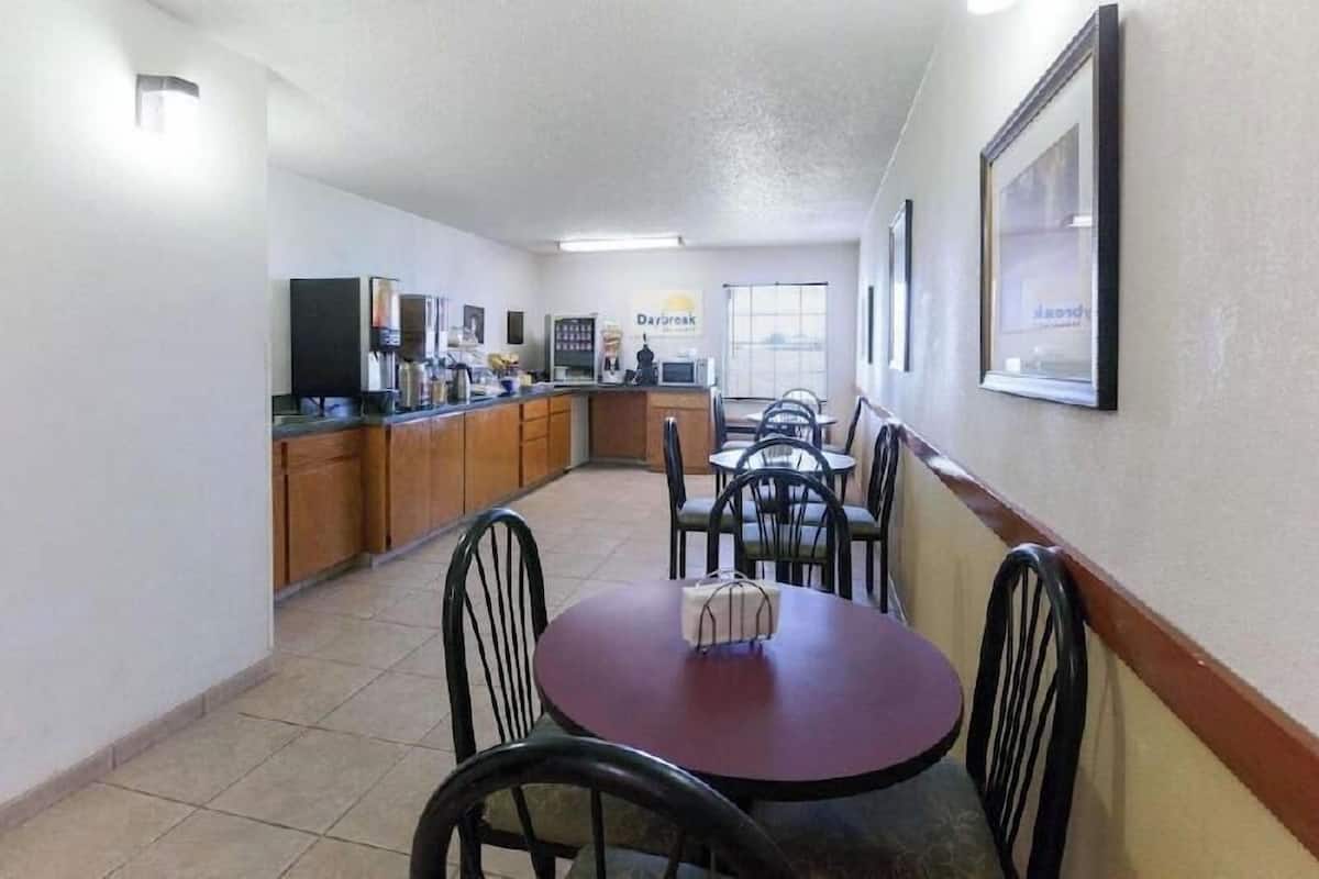 A small, clean room with a kitchenette, a dining table with chairs, and a sign that reads 'Daybreak.'