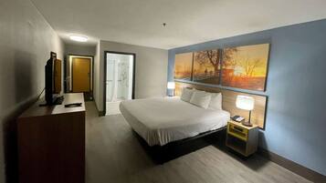 A hotel room with a bed, bedside lamp, and a painting on the wall.