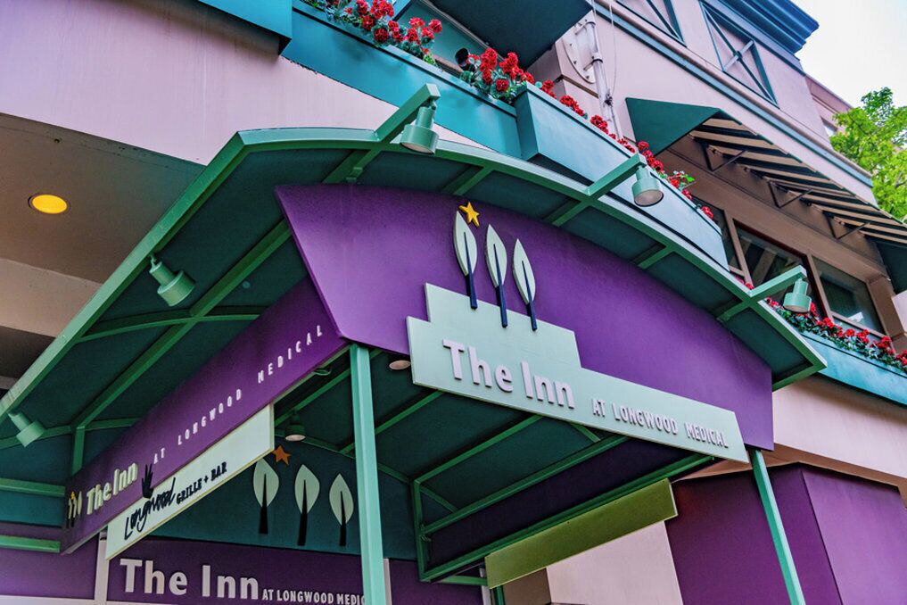 The Inn at Longwood Medical, featuring a purple facade with green accents and a signboard.