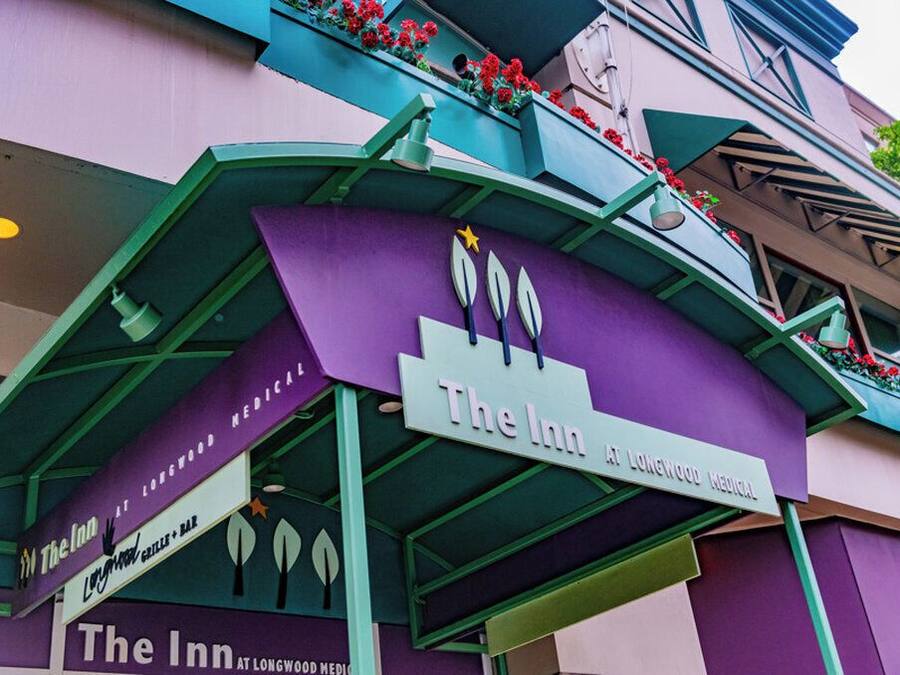 The Inn at Longwood Medical, featuring a purple facade with green accents and a signboard.