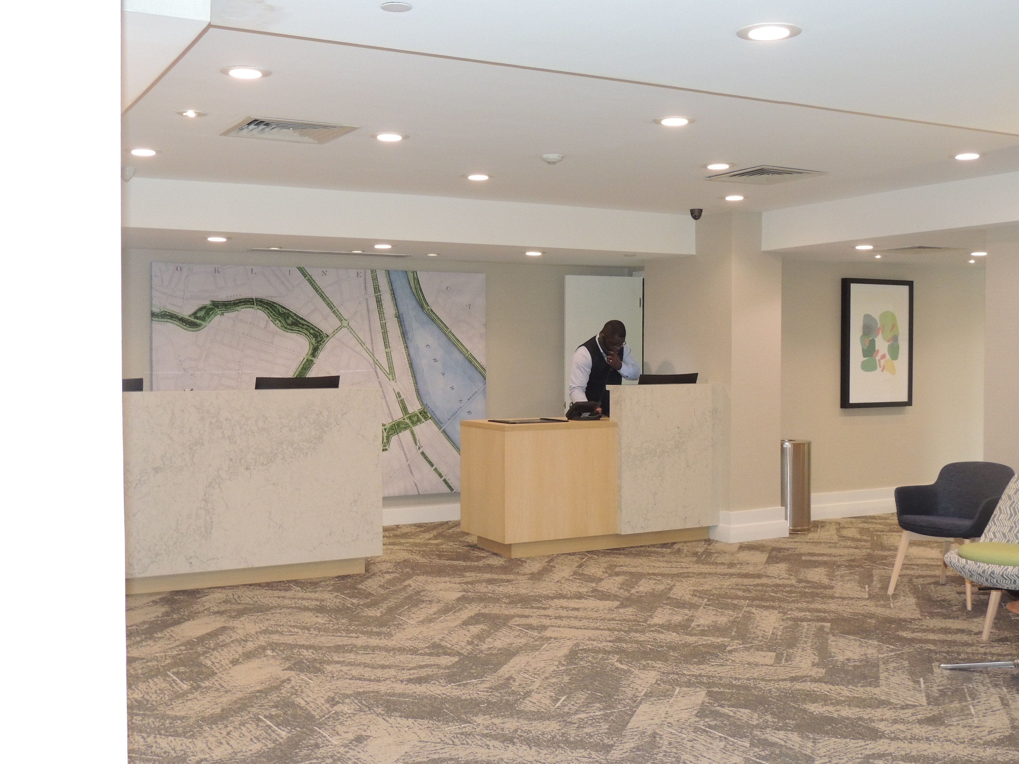 A reception area with a marble reception desk, a large map on the wall, and a seating area with a chair.