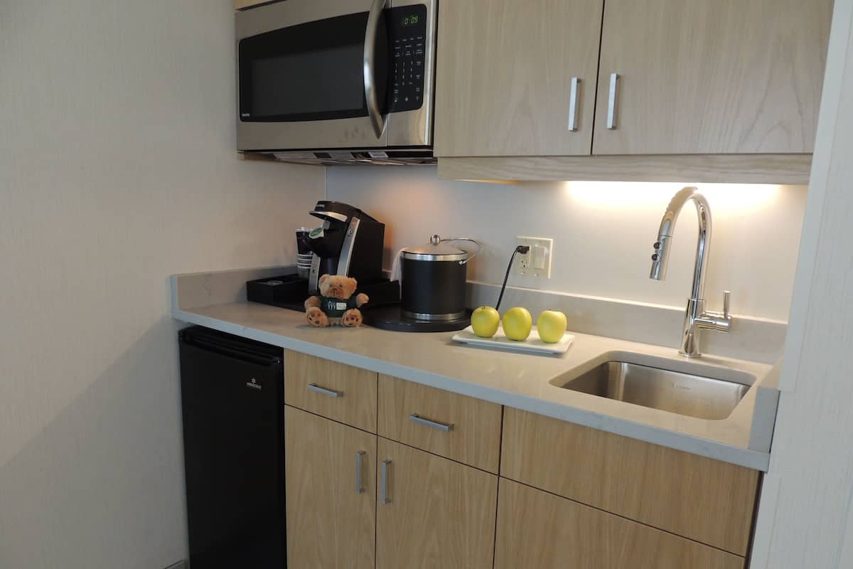A modern kitchen with a microwave, coffee maker, and a sink.