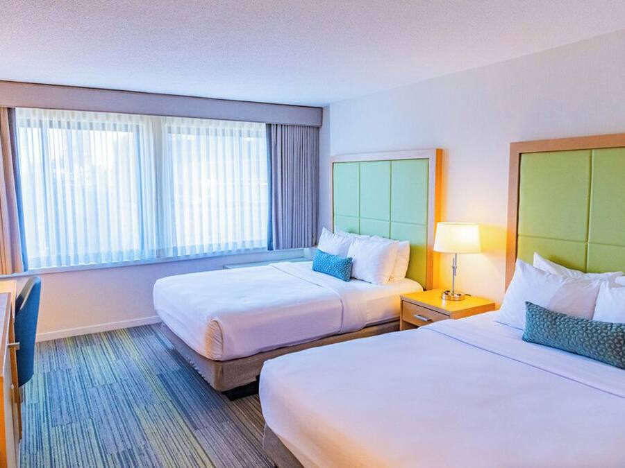 A hotel room with two beds, a desk, and a chair.