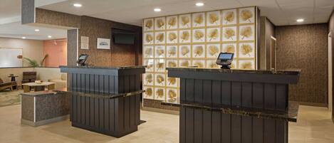 A reception area with two counters, a wall-mounted TV, and a patterned wall.