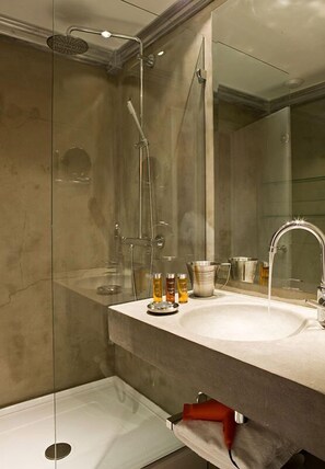 A modern bathroom with a glass-enclosed shower, a large mirror, and a vanity with a sink and toiletries. - Hotel Ormelune (Val-d'Isere)