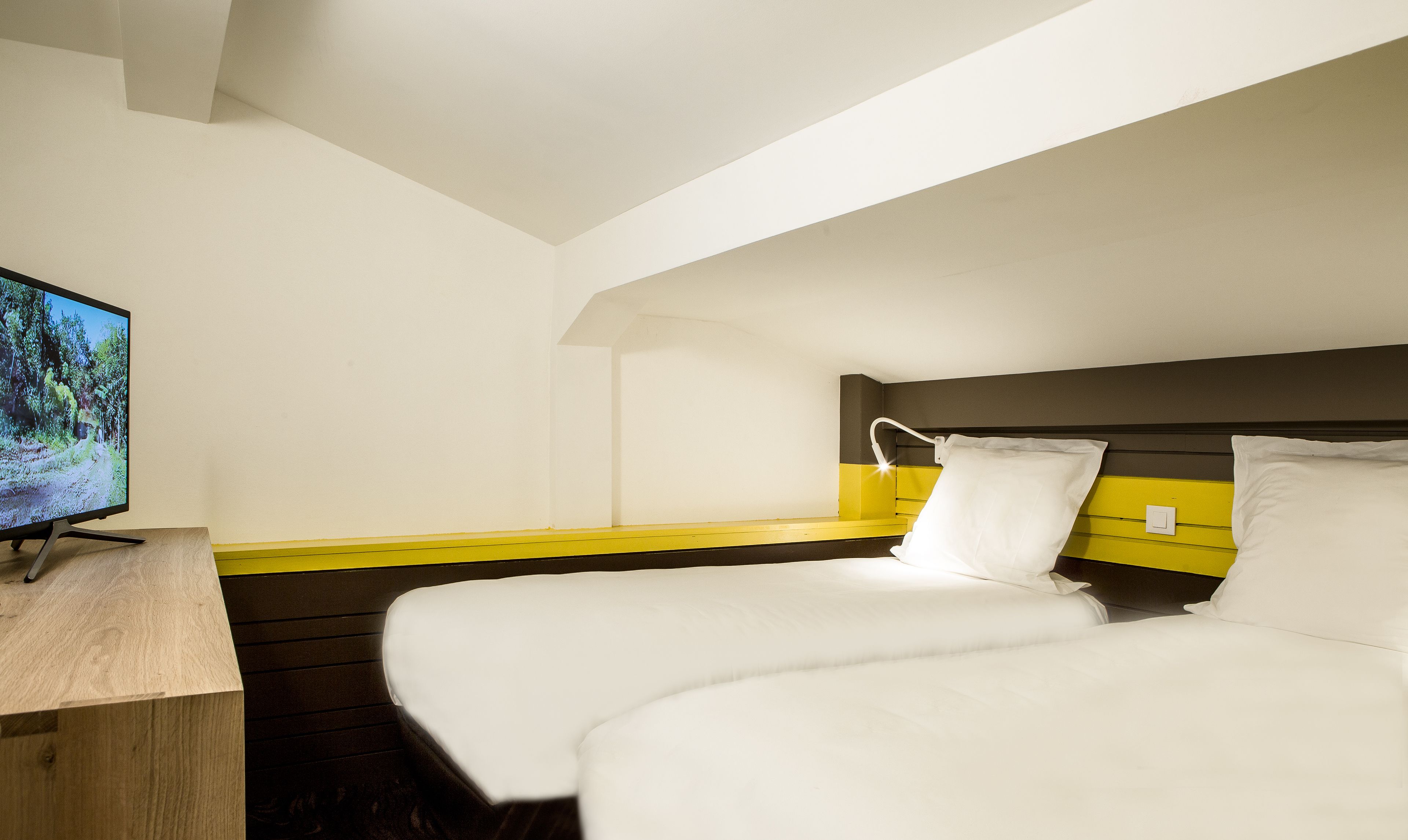 Una habitación de hotel con una cama, una mesita de noche y un televisor en la pared.