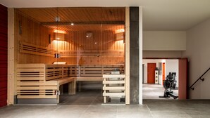 A sauna room with wooden benches and a glass partition. - Hotel Ormelune (Val-d'Isere)