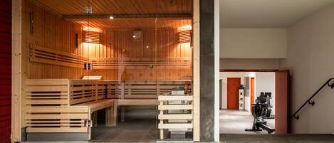 A sauna room with wooden benches and a glass partition.