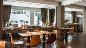 A dining area with a long table set for multiple people, surrounded by chairs. - Hotel Ormelune (Val-d'Isere)