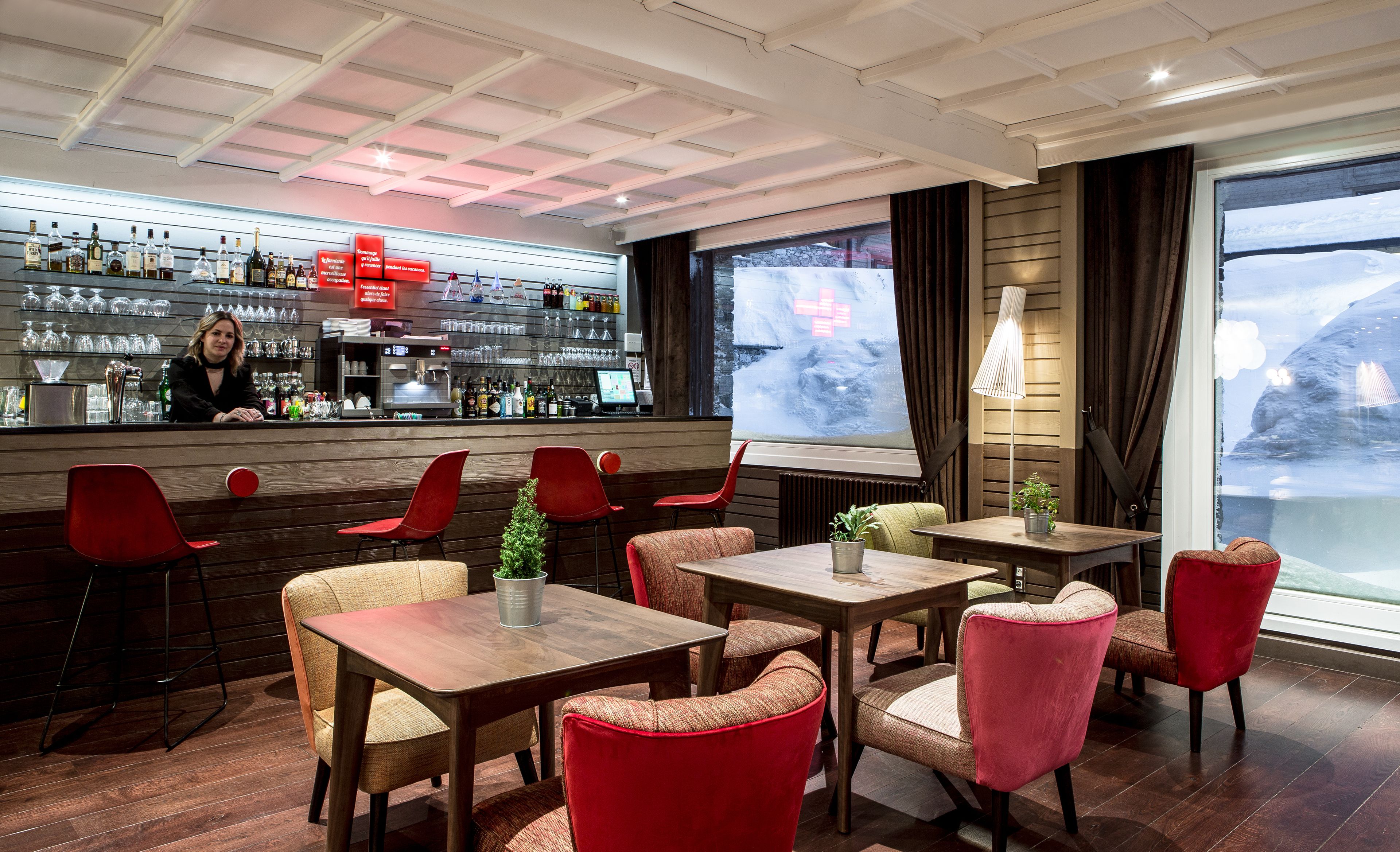 A bar area with a counter, shelves with bottles, and a seating area with tables and chairs.