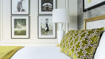 A neatly arranged hotel room with a bed, a white lamp, and framed photographs on the wall.