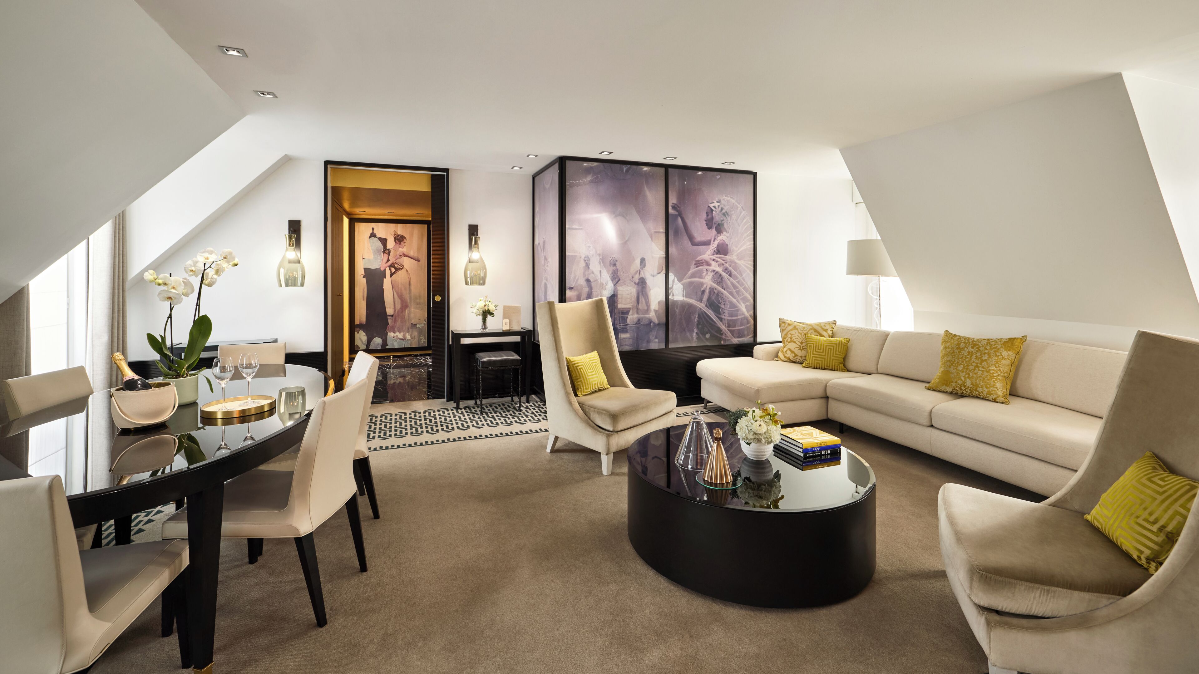 Un salon moderne comprenant un coin repas, un ensemble de canapés, une table basse et un tableau accroché au mur.