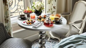 Una mesa de desayuno con diversas opciones de comida, un florero y vistas al exterior.