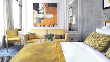 Ein Hotelzimmer mit einem großen Bett, einer Couch, einem Sessel, einem Bild an der Wand und einem Fenster.